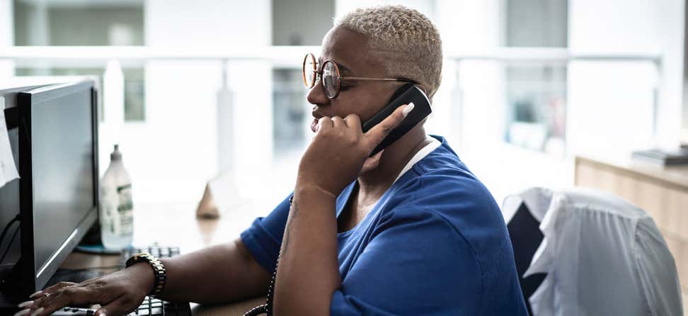 A medical administrative assistant takes a call while admitting new patients into the hospital.