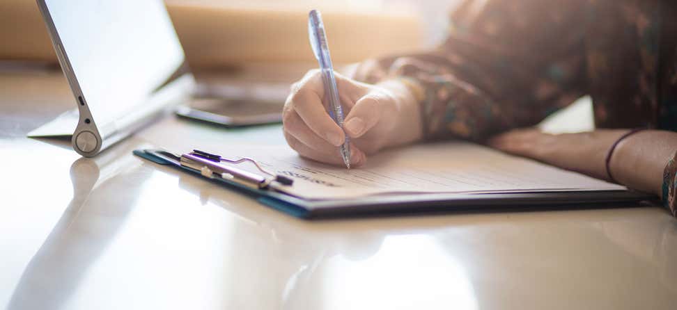 A woman is seen filling out paperwork on a clipboard.