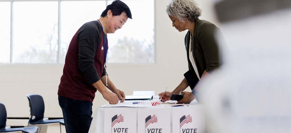 A senior Black woman is filling out her ballot at the polls.