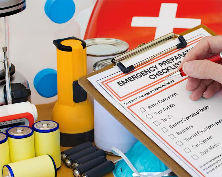 A up close shot of an emergency preparedness checklist along with the items on the list, like batteries and others.