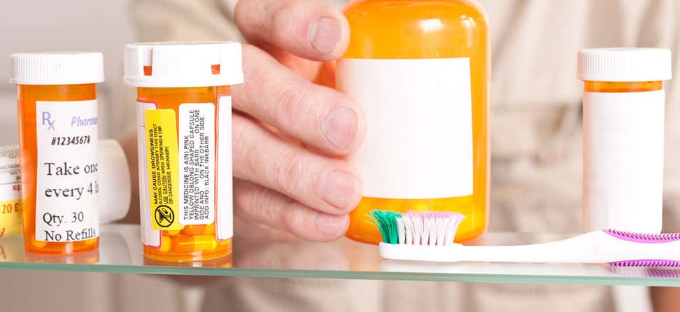Older hand reaching for prescriptions in medicine cabinet