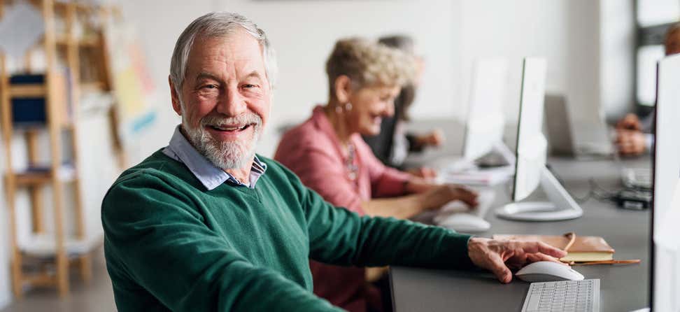 Senior man in green shirt sitting at computer