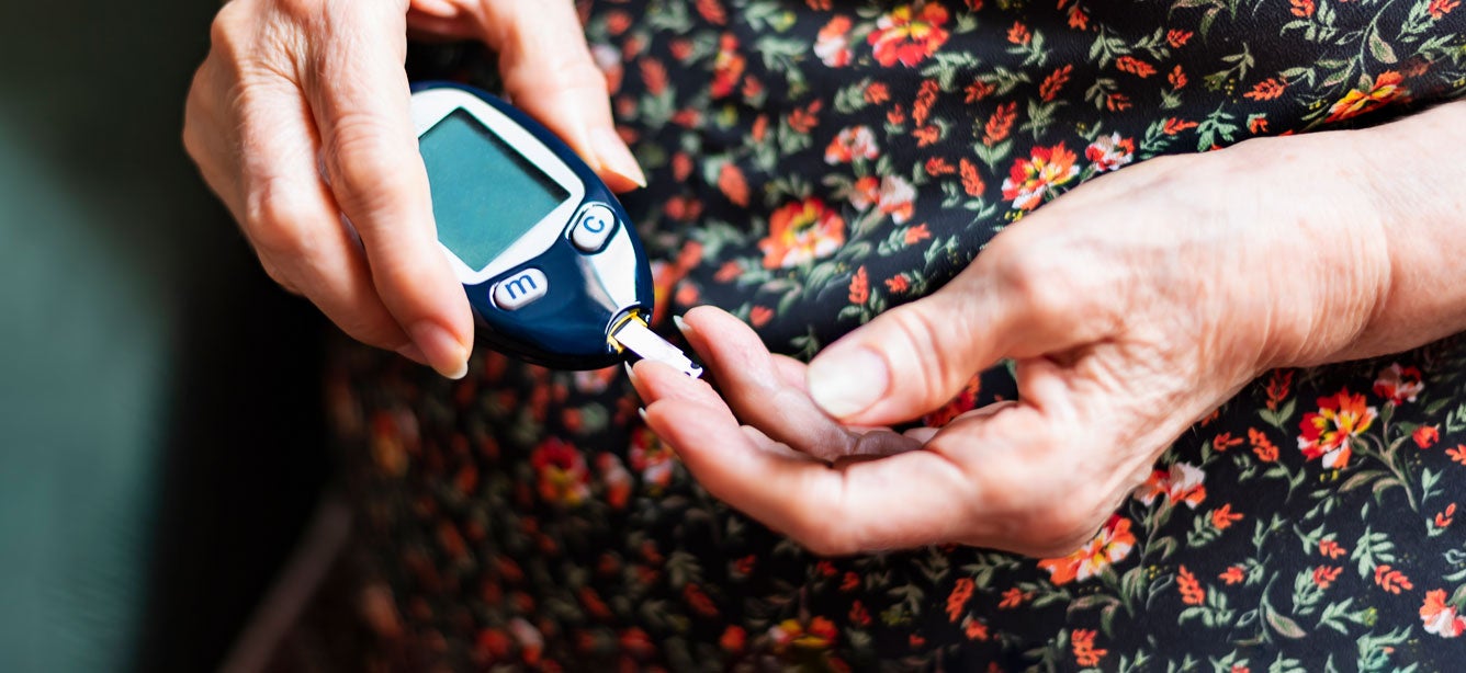A senior woman is monitoring her glucose levels.