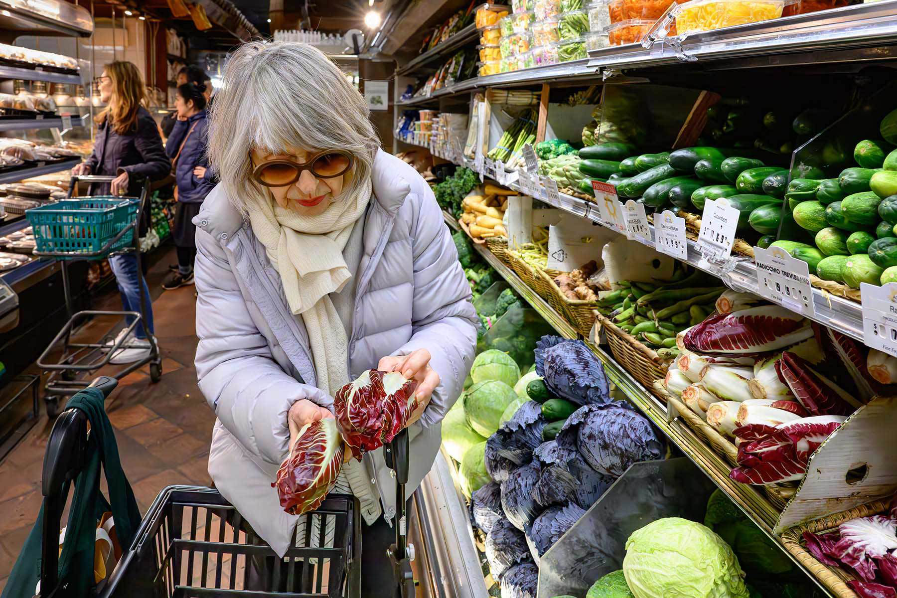 a woman looking at red cabbage in a grocery store