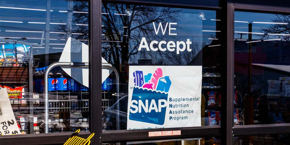 A "We Accept Supplemental Nutrition Assitance Program (SNAP)" sign appears on the window of a grocery retailer.