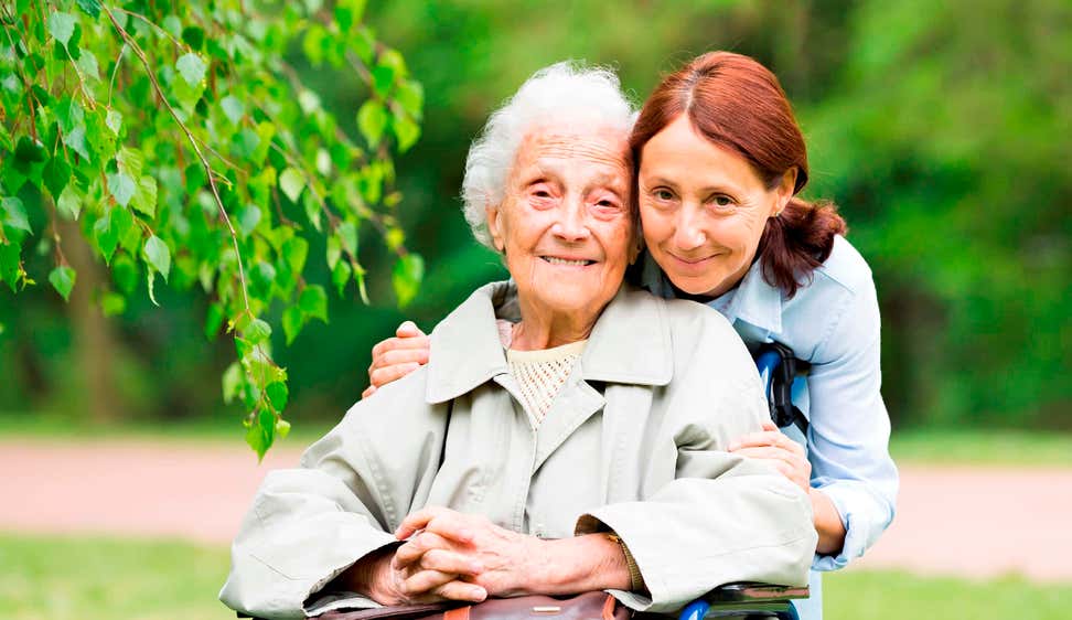 Senior Caucasian woman in wheelchair with caregiver outside in garden