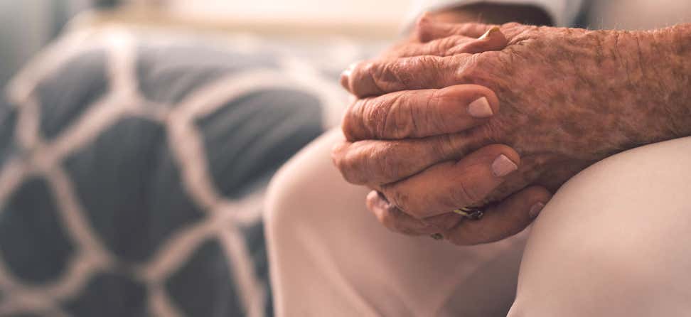 A close up shot of a senior man's hands folded on his lap.