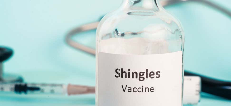 A close up shot of a Shingles vaccine vial with a syringe in the foreground.