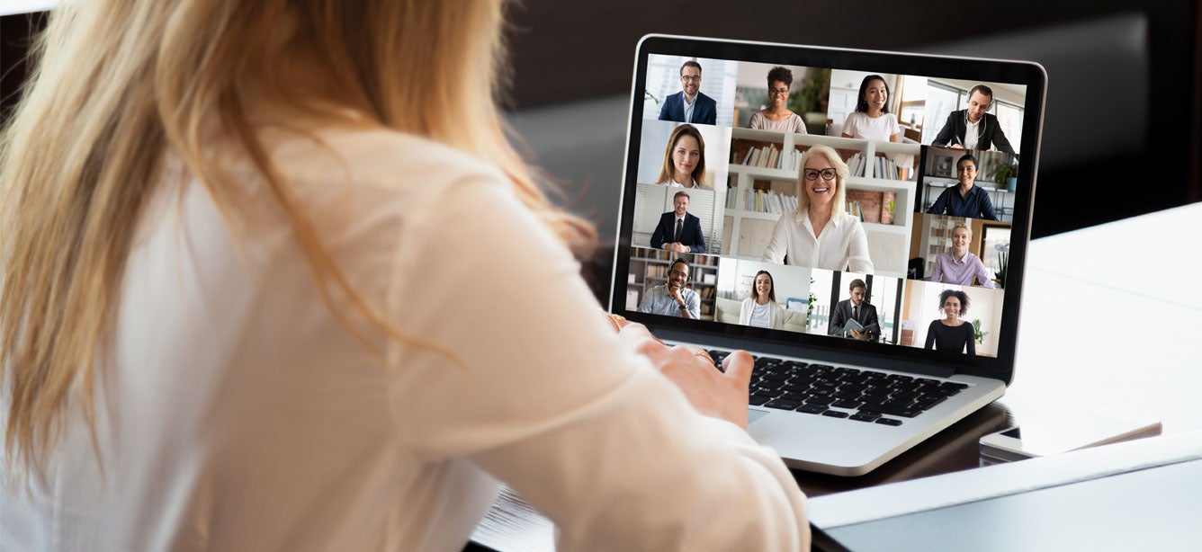 A younger Caucasian female is seen communicating with her colleagues in a webinar.