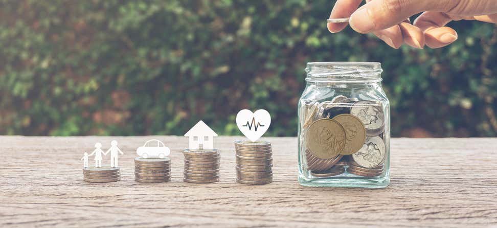 Stacks of coins are lined up, with amounts ranging from lower to highest - symbolizing what you save for your family, a car, house, and health. A hand is dropping some of the coins in a mason jar.