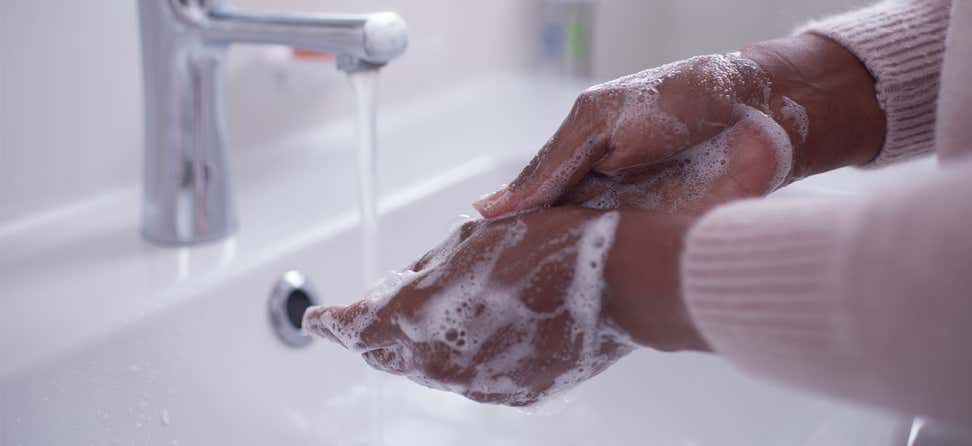 Close up shot of a Black woman washing her hands under running tap water.
