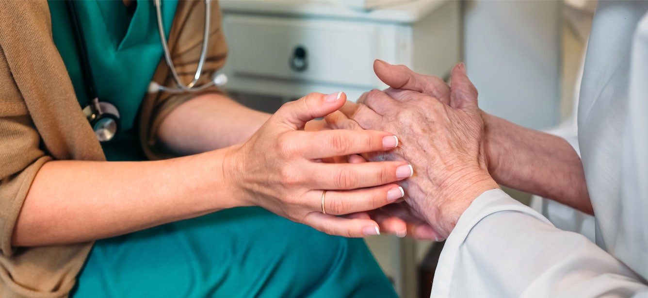 A nurse holds the hands of a female senior.