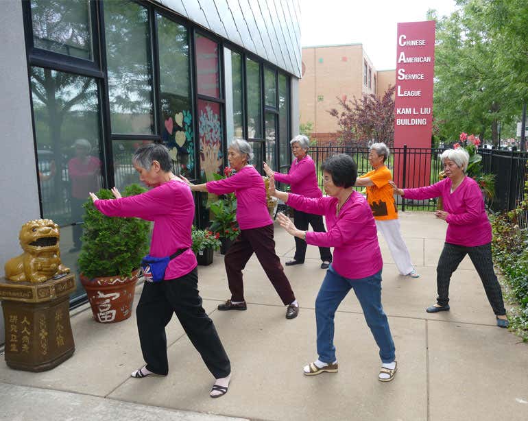Chinese American women in pink shirts practicing tai chi outside