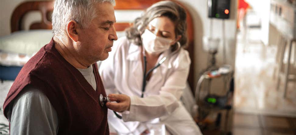 A health care worker/nurse is visiting a senior man, using a digital tablet.