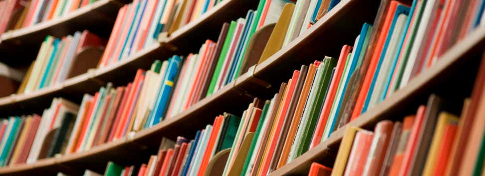 A photo of a library's shelves with many colorful books.