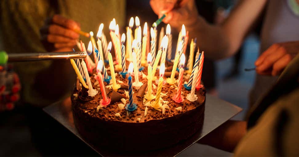 A close up shot of a birthday cake with a lot of candles being lit.