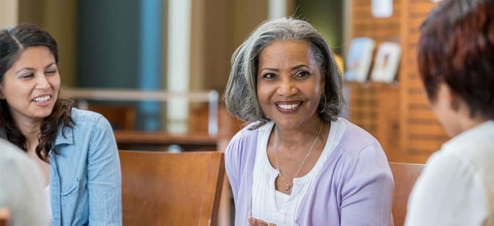 A black senior woman works with a group in a casual setting.