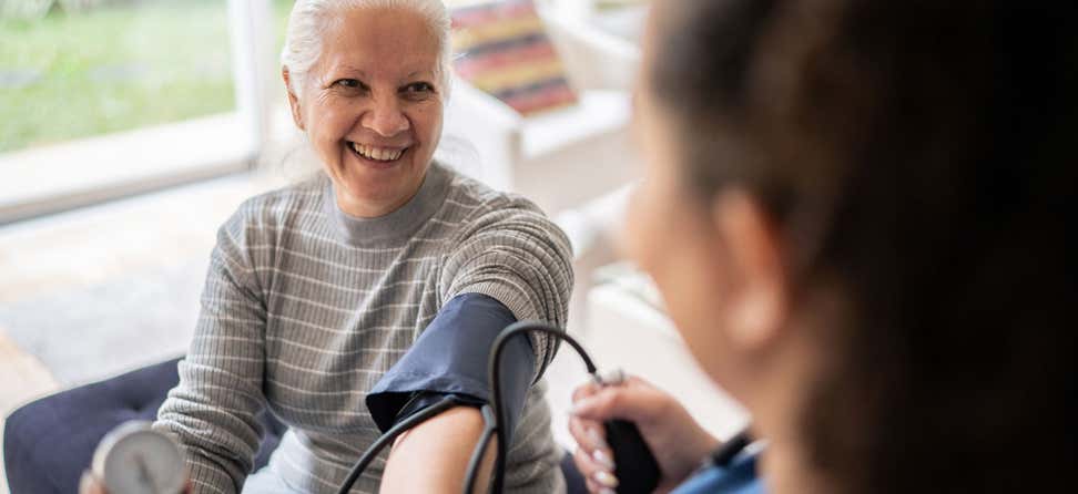 A senior Caucasian woman is having her blood pressure checked while receiving care in her home.