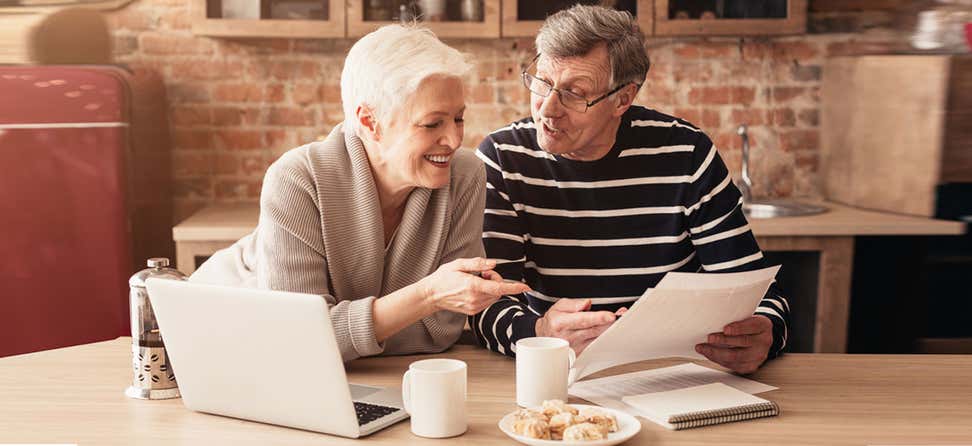 A senior couple is sitting at their kitchen table looking over their Medicare plan options.