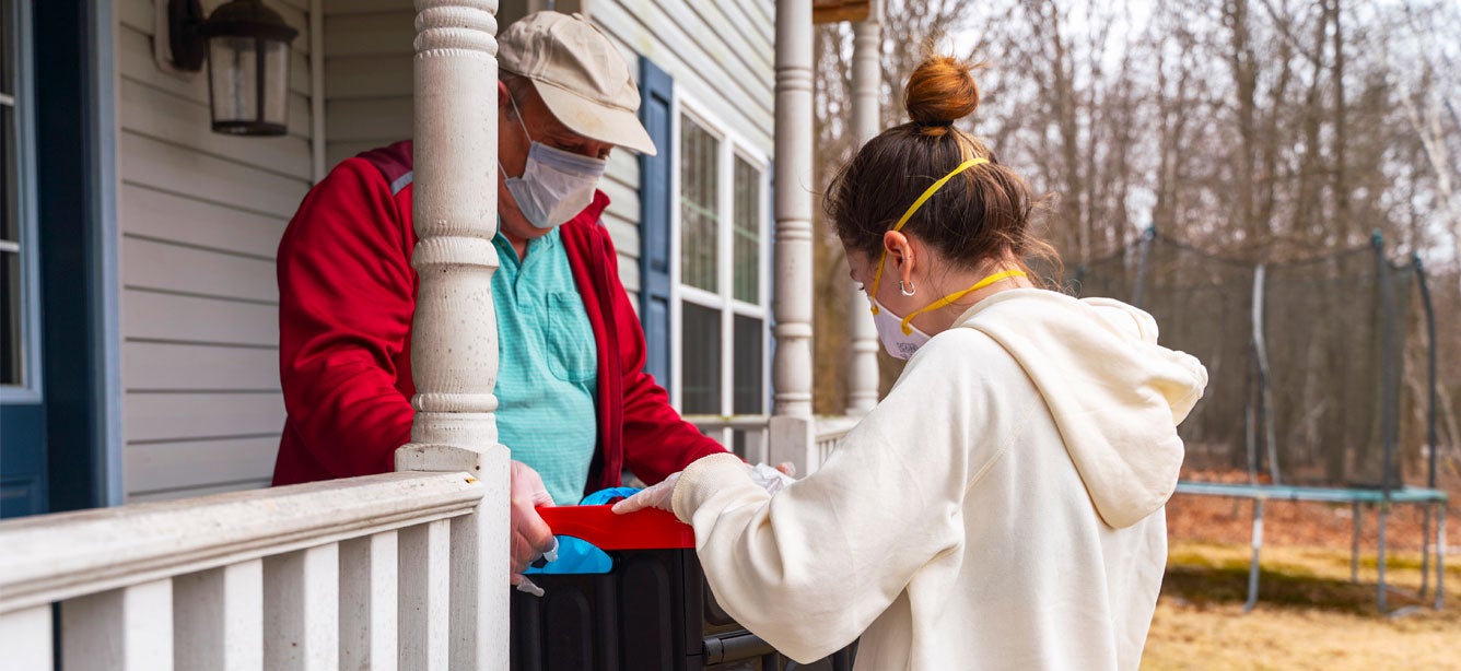 An older man receives a grocery delivery at home during the COVID-19 coronavirus outbreak.